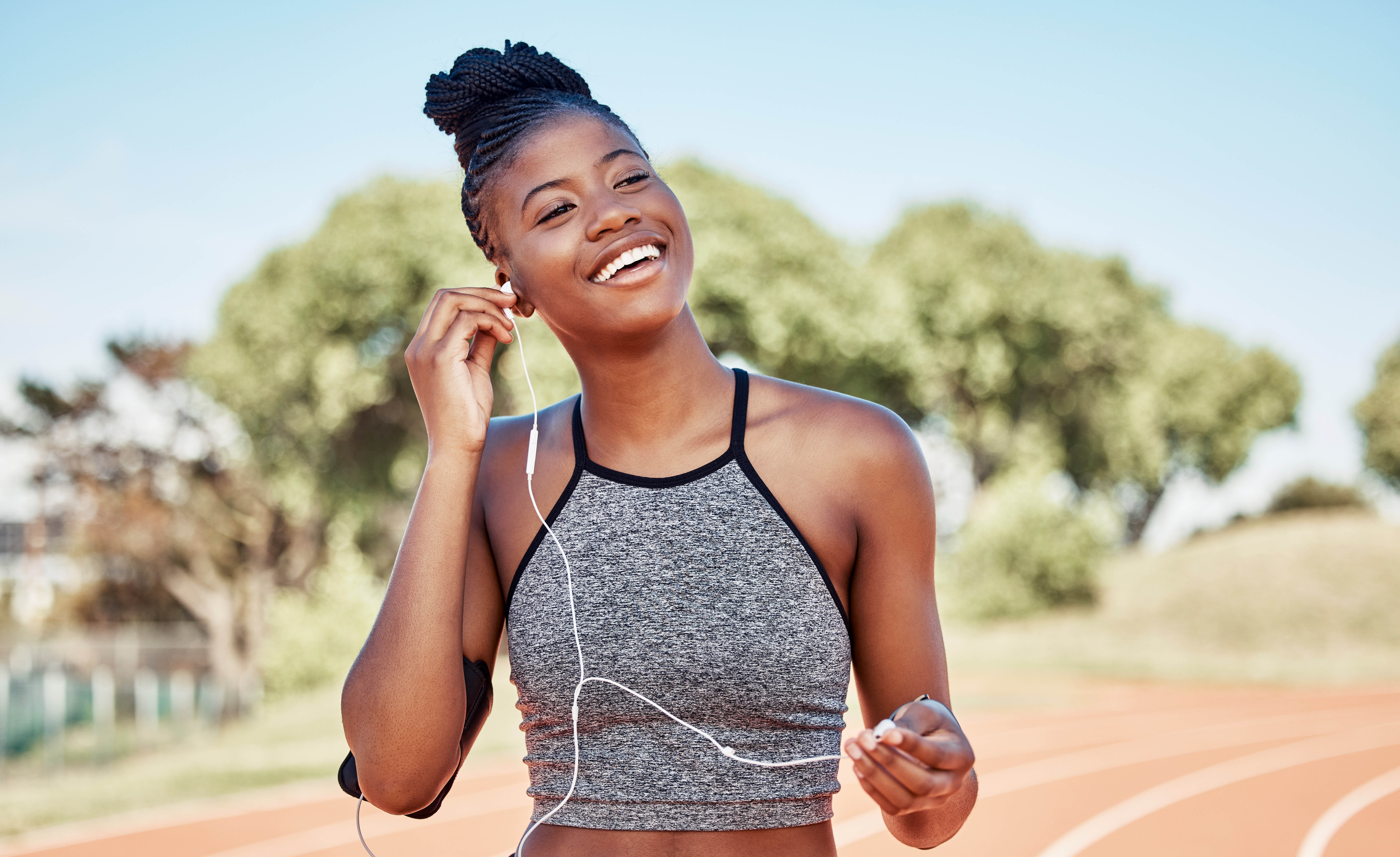 Young black woman, smiling as she puts her headphones in to start her workout